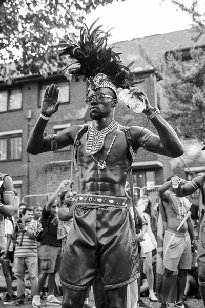 Black-painted men pose for a photo. It used to be black oil but they  replaced it with black paint to cover the body. The Notting Hill Carnival  is one of the biggest